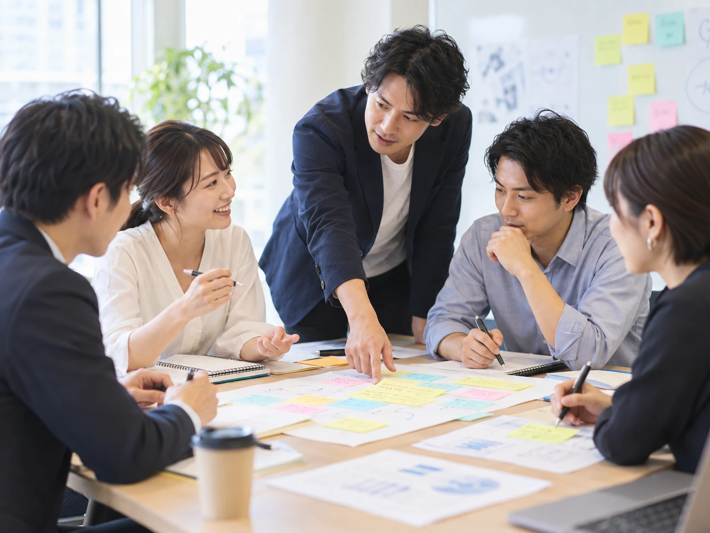 付箋を広げた資料を囲み、講師と受講生が議論するグループワーク